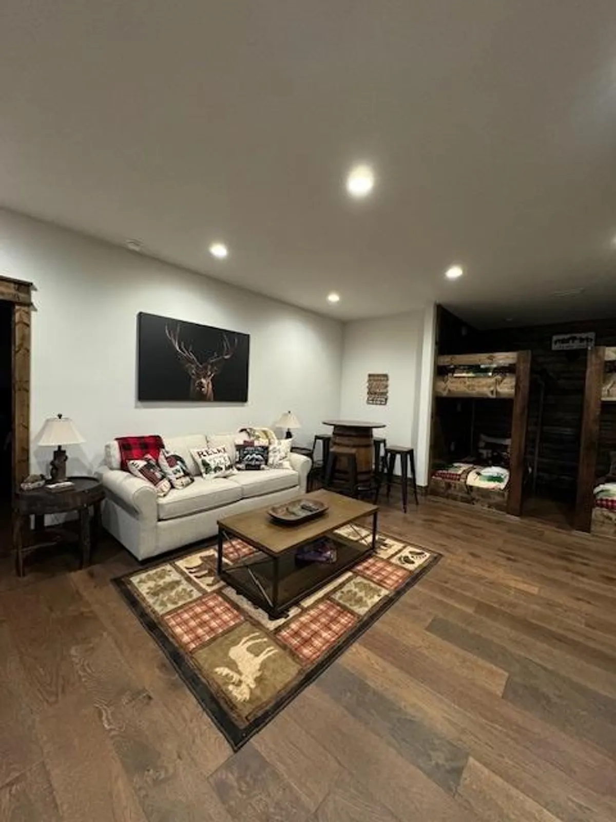 A comfortable, family-friendly seating area with a sofa, coffee table, and a background view of bunk beds. The playful decor (including wall art) and inviting setup suggest a space for both relaxation and interactive family fun.